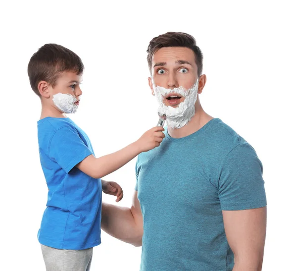 Mały syn stosując piankę do golenia na twarz taty na białym tle — Zdjęcie stockowe