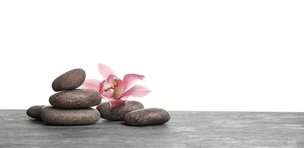 Orchid flower with spa stones on table against white background — Stock Photo, Image