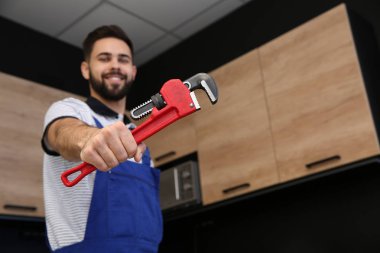 Erkek tesisatçı mutfakta boru anahtarı tutuyor, metin için yer. Onarım hizmeti