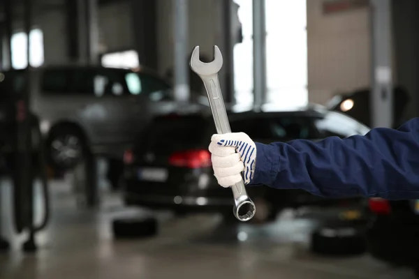 Técnico que sostiene la llave en el taller de reparación de automóviles, primer plano —  Fotos de Stock