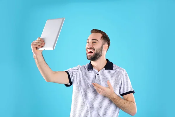 Homem usando tablet para bate-papo por vídeo em fundo de cor — Fotografia de Stock