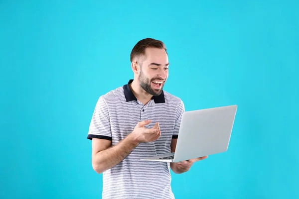Człowiek za pomocą laptopa do rozmów wideo na kolorowym tle — Zdjęcie stockowe