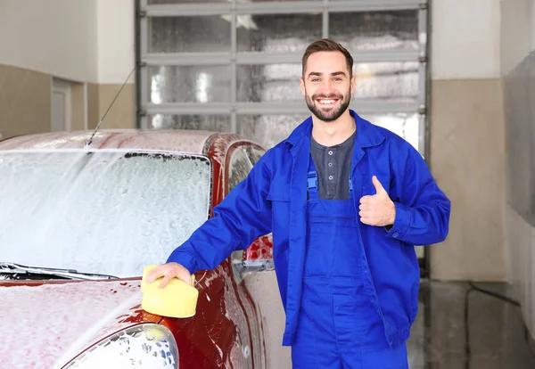 Retrato de trabalhador com esponja perto de auto na lavagem de carro — Fotografia de Stock