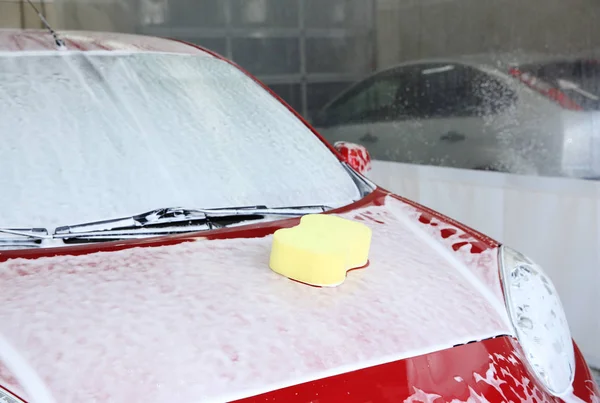 Automóvel com esponja em seu capot na lavagem de carros — Fotografia de Stock