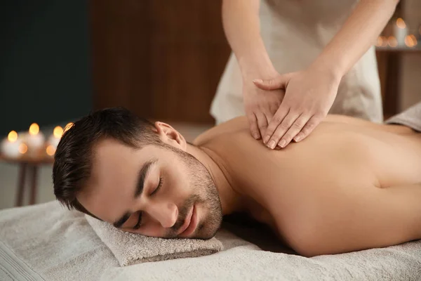 Bonito homem recebendo massagem de volta no salão de spa — Fotografia de Stock