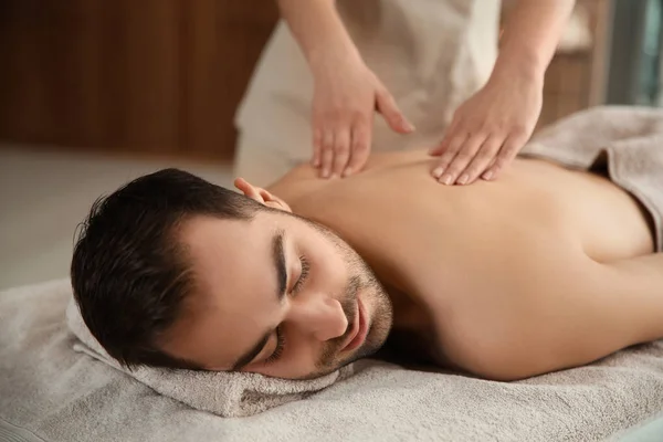 Hombre guapo recibiendo masaje de espalda en el salón de spa — Foto de Stock