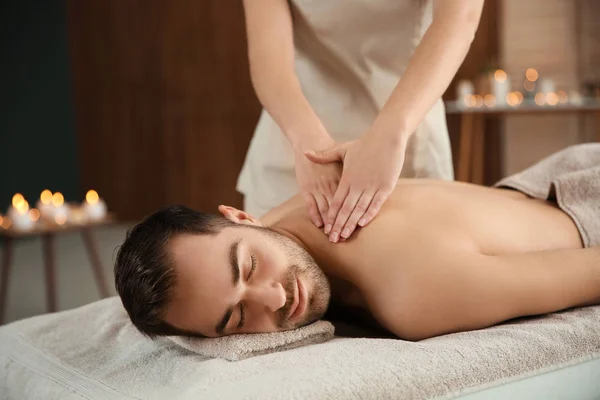 Bonito homem recebendo massagem de volta no salão de spa — Fotografia de Stock