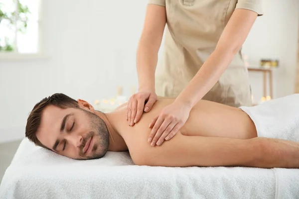 Bonito homem recebendo massagem de volta no salão de spa — Fotografia de Stock