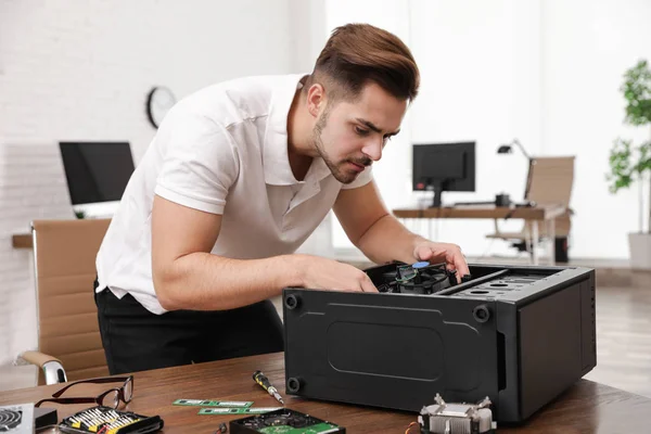 Técnico masculino que repara la computadora en la mesa en el interior —  Fotos de Stock