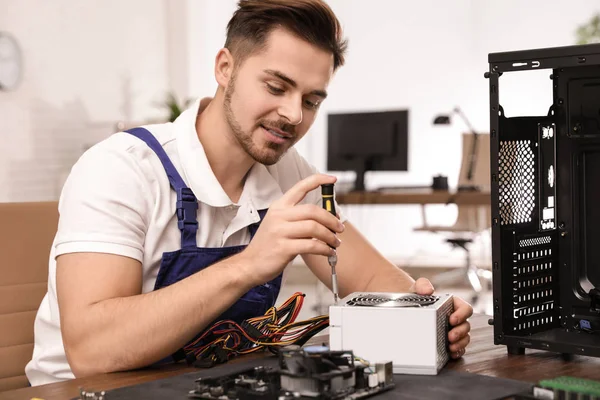 Técnico masculino reparando la unidad de fuente de alimentación en la mesa en el interior —  Fotos de Stock