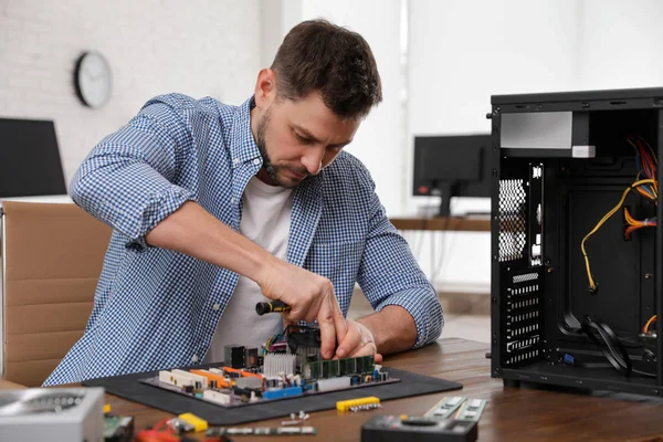Male technician repairing motherboard at table indoors — Stock Photo, Image