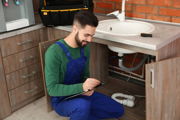 Mannelijke loodgieter met Klembord in de buurt van keuken gootsteen. Reparatie service — Stockfoto
