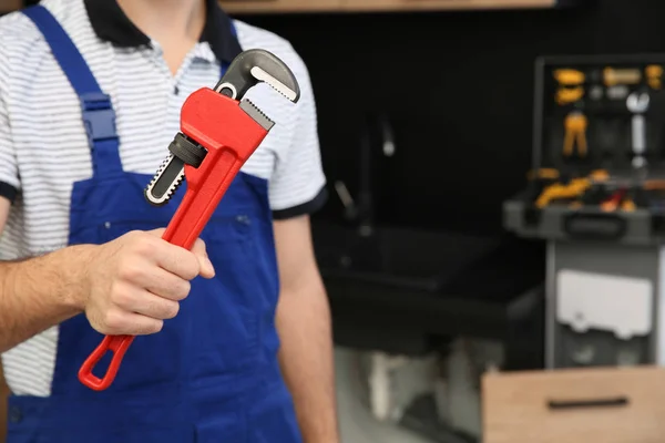 Plomero masculino sosteniendo llave de tubo en la cocina, primer plano con espacio para el texto. Servicio de reparación — Foto de Stock