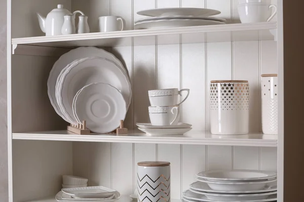 Elegante soporte de almacenamiento con diferentes vajilla de cerámica en casa —  Fotos de Stock
