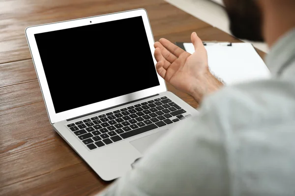 Чоловік використовує відео чат на ноутбуці в домашньому офісі, крупним планом. Простір для тексту — стокове фото