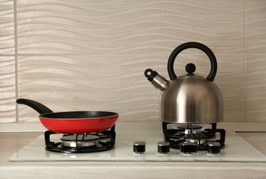 Çelik su ısıtıcısı ve modern gaz sobası üzerinde tava kızartma. Metin için alan