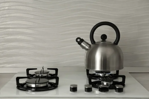 Steel kettle with whistle on modern gas stove. Space for text