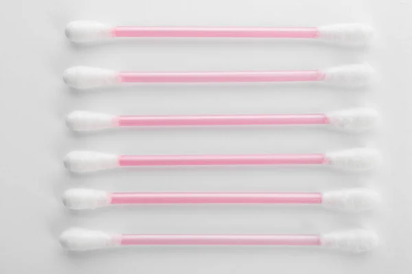 Pink plastic cotton swabs on white background, top view