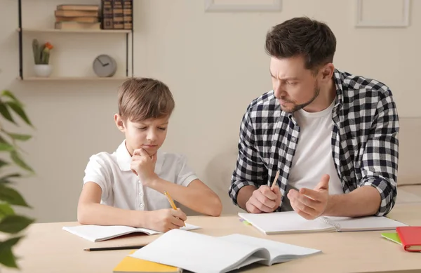 お父さんは自宅で学校の宿題で彼の息子を助けるために苦労 — ストック写真