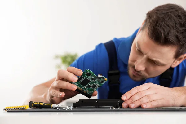 Male technician repairing hard drive at table indoors