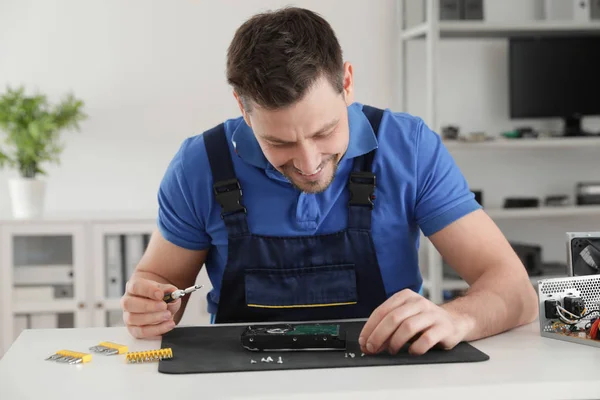 Técnico masculino reparando el disco duro en la mesa en el interior —  Fotos de Stock