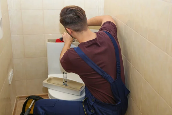 Encanador masculino reparando tanque sanitário no banheiro — Fotografia de Stock