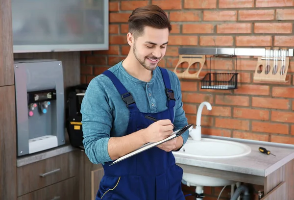 Plomero masculino con portapapeles en la cocina. Servicio de reparación — Foto de Stock