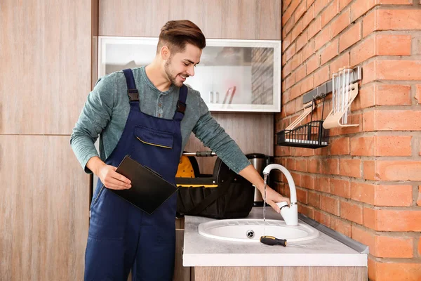 Αρσενικό υδραυλικός σε ομοιόμορφη έλεγχο βρύσης στην κουζίνα. Υπηρεσία επισκευής — Φωτογραφία Αρχείου