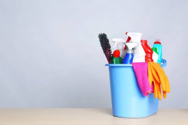 Gri arka plana karşı masada temizlik malzemeleri ile Kova. Metin için alan