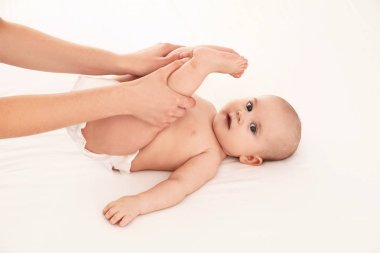 Anne ve tatlı çocuğu beyaz yatakta. Bebek masajı ve egzersizler.