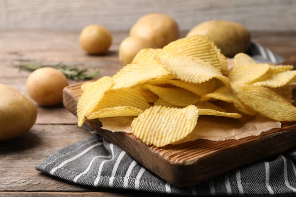 Bord met knapperige aardappel chips op houten tafel — Stockfoto