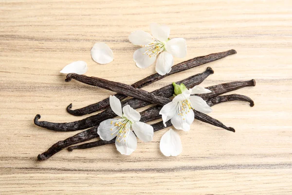 Flat lay composition with aromatic vanilla sticks and flowers on wooden background — Stock Photo, Image