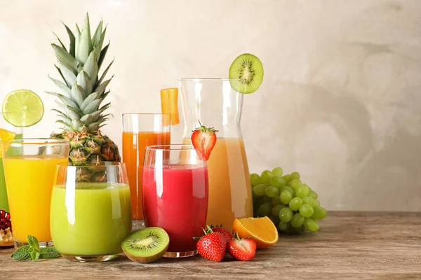 Скляний посуд з різними соками та свіжими фруктами на столі. Простір для тексту — стокове фото