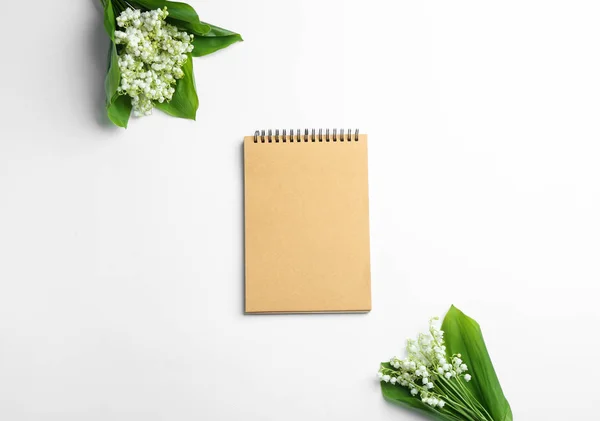 Notebook and lily of the valley bouquets on white background, flat lay. Space for text — Stock Photo, Image