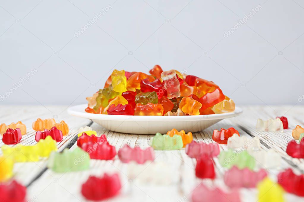 Plate with delicious jelly bears on wooden table