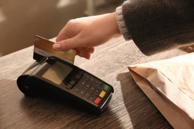 Kredi kartı olan bir kadın dükkandaki ödeme terminalini kullanıyor.