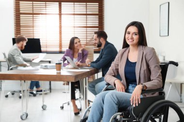 Ofiste meslektaşları ile tekerlekli sandalyede genç kadın