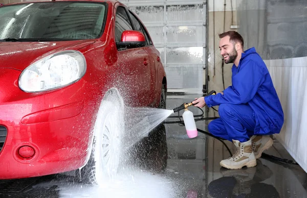 Pracovník čistí automobil s vysokotlakým proudem vody v myčce aut — Stock fotografie