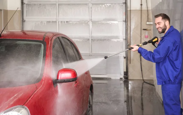 Travailleur nettoyage automobile avec jet d'eau haute pression au lavage de voiture — Photo