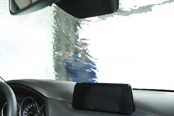 Pulizia dei lavoratori parabrezza dell'automobile con getto d'acqua ad alta pressione all'autolavaggio, vista dall'interno — Foto Stock