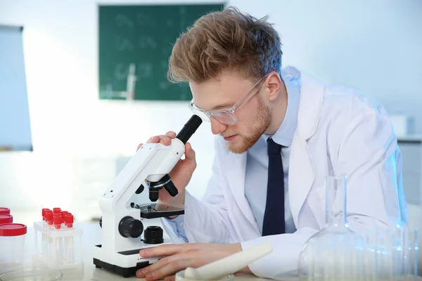 Homme scientifique utilisant un microscope moderne en laboratoire de chimie — Photo