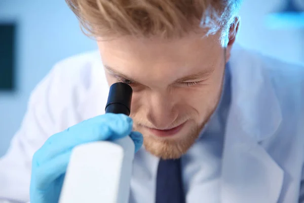 Мужчина-ученый, использующий современный микроскоп в химической лаборатории — стоковое фото