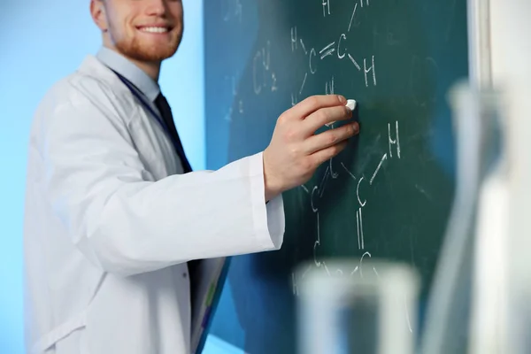 Cientista masculino escrevendo fórmula química em quadro-negro dentro de casa, close-up — Fotografia de Stock