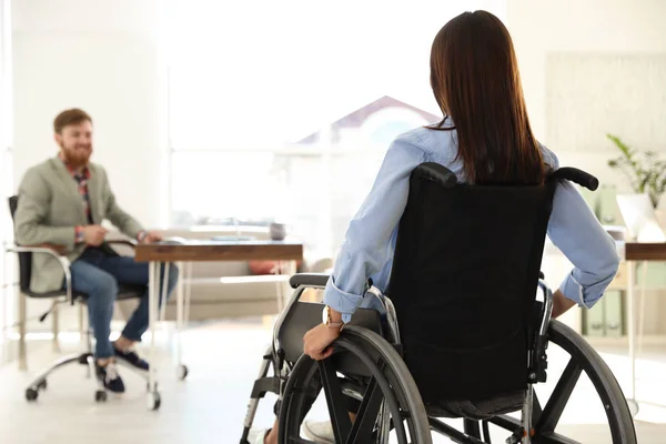 Νεαρή γυναίκα σε αναπηρικό αμαξίδιο με συνάδελφο στο γραφείο — Φωτογραφία Αρχείου