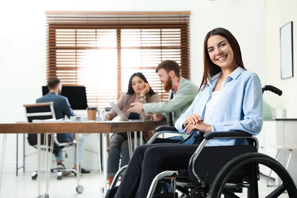 Giovane donna in sedia a rotelle con colleghi in ufficio — Foto Stock