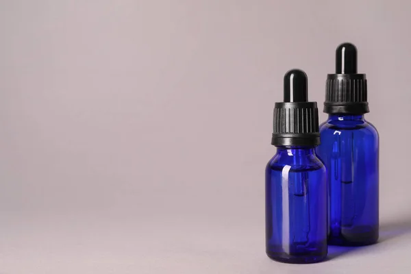 Cosmetische flessen van etherische oliën op kleur achtergrond. Ruimte voor tekst — Stockfoto