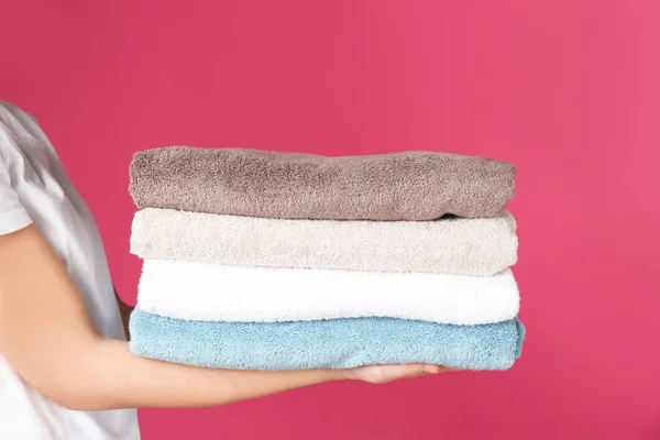 Jovem segurando toalhas limpas no fundo da cor, close-up. Dia de lavandaria — Fotografia de Stock