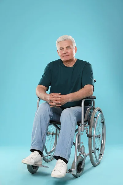 Старший чоловік у інвалідному візку на кольоровому фоні — стокове фото