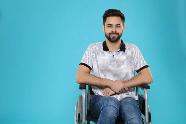 Young man in wheelchair on color background. Space for text