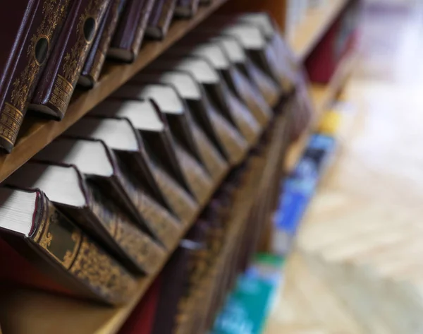 Wooden cabinet with collection of books in library, closeup. Space for text